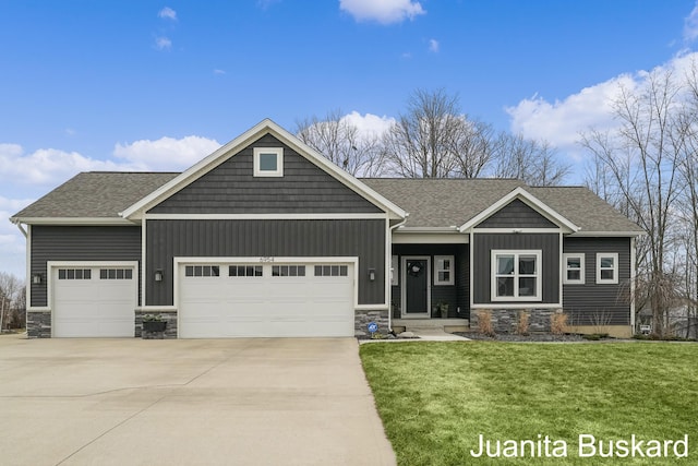 craftsman-style house with driveway, an attached garage, a front lawn, stone siding, and board and batten siding