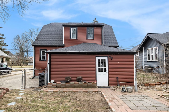 back of house featuring roof with shingles, fence, a gate, and central air condition unit