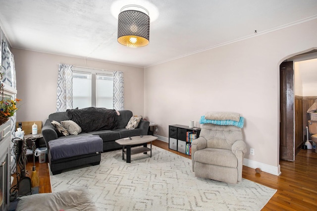 living room featuring arched walkways, crown molding, wood finished floors, and baseboards