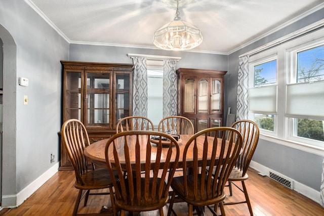 dining space featuring visible vents, arched walkways, wood-type flooring, and baseboards