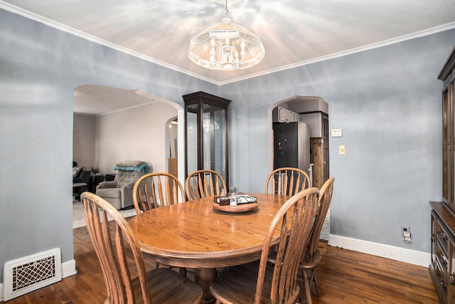 dining area featuring arched walkways, wood finished floors, visible vents, baseboards, and crown molding