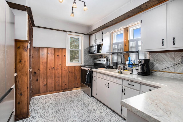 kitchen featuring black microwave, wooden walls, white cabinets, light countertops, and stainless steel electric stove