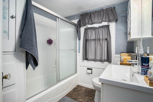 bathroom featuring combined bath / shower with glass door, vanity, and toilet