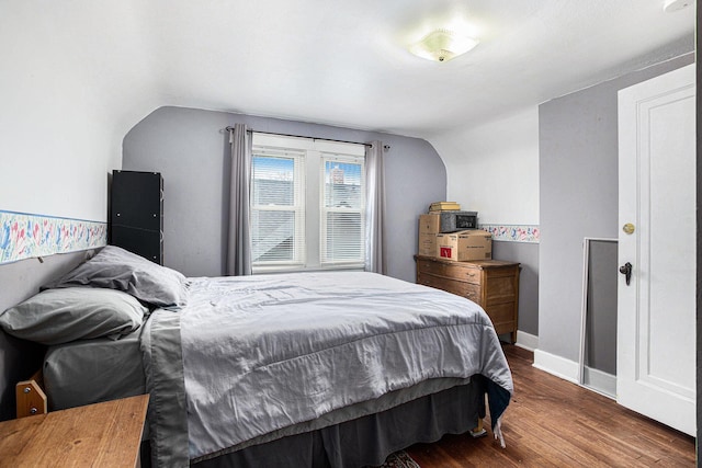 bedroom with lofted ceiling, dark wood-style floors, and baseboards