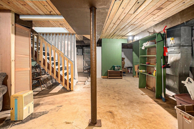 finished basement featuring wood ceiling, electric panel, and stairway