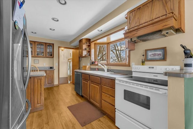 kitchen featuring light wood-style flooring, brown cabinets, stainless steel appliances, premium range hood, and a sink