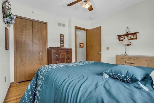 bedroom featuring visible vents, baseboards, a ceiling fan, light wood-style flooring, and a closet