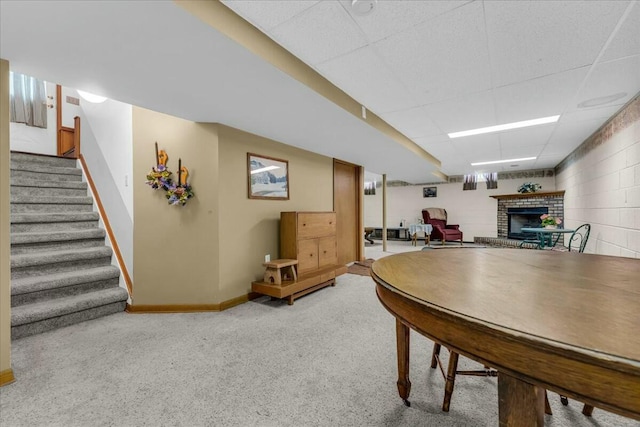 interior space featuring concrete block wall, baseboards, stairway, a paneled ceiling, and a brick fireplace