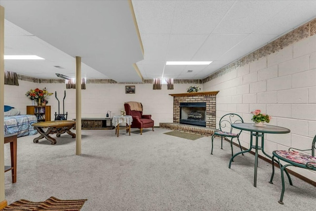 carpeted living room featuring concrete block wall and a fireplace