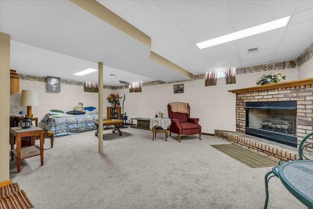 living area with a fireplace, visible vents, electric panel, carpet, and concrete block wall