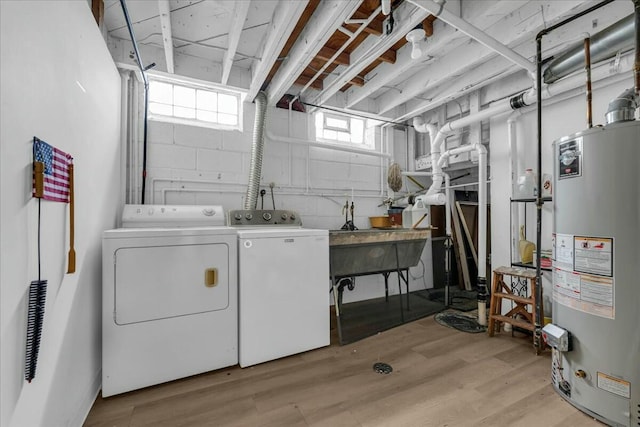 washroom featuring laundry area, separate washer and dryer, light wood-type flooring, and gas water heater