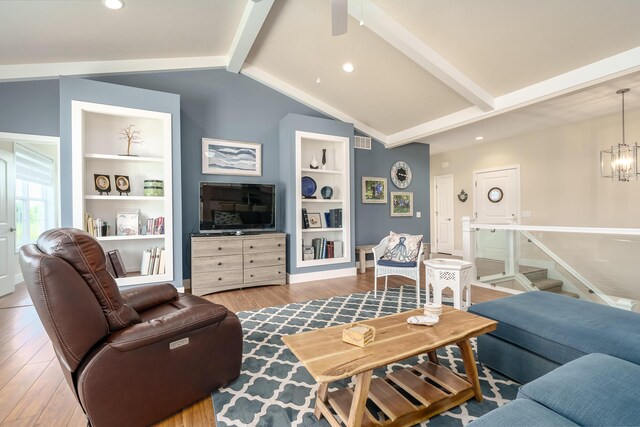 living area featuring built in features, visible vents, lofted ceiling with beams, an inviting chandelier, and wood finished floors