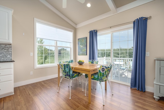 dining room with lofted ceiling with beams, wood finished floors, and baseboards