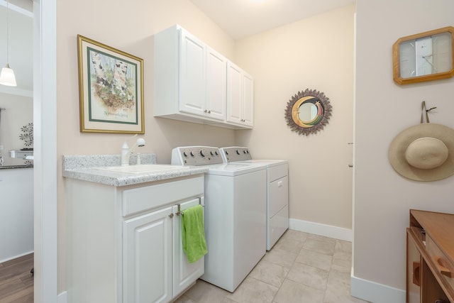 clothes washing area featuring cabinet space, washer and clothes dryer, baseboards, and light tile patterned flooring