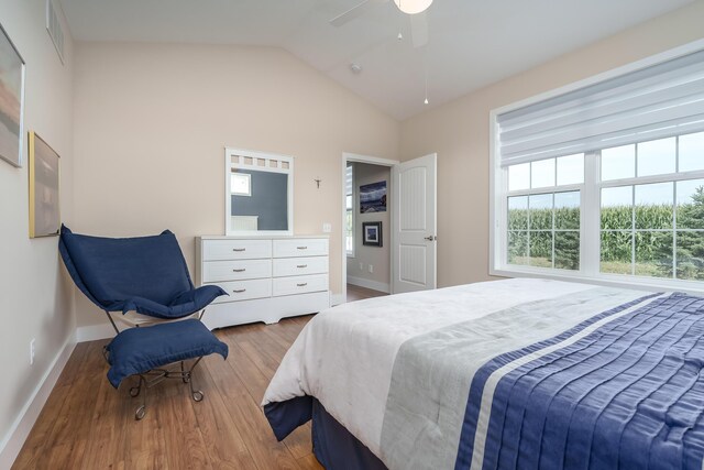 bedroom featuring lofted ceiling, wood finished floors, visible vents, a ceiling fan, and baseboards