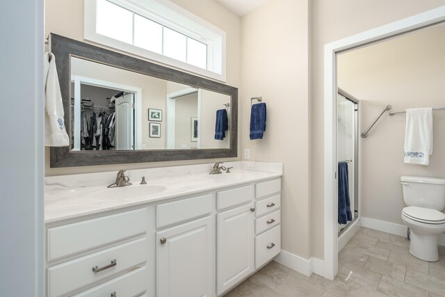 bathroom featuring toilet, a stall shower, double vanity, and a sink