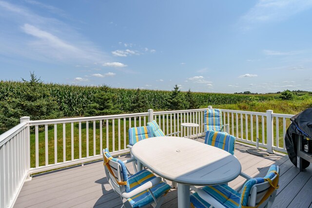 wooden deck featuring a grill, a rural view, and outdoor dining space