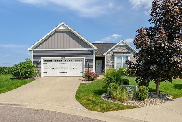 craftsman inspired home with stone siding, a front lawn, and an attached garage