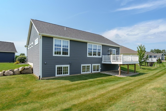 back of property featuring a shingled roof, a deck, and a lawn
