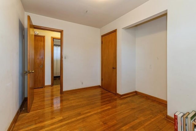 unfurnished bedroom with a closet, baseboards, and wood finished floors