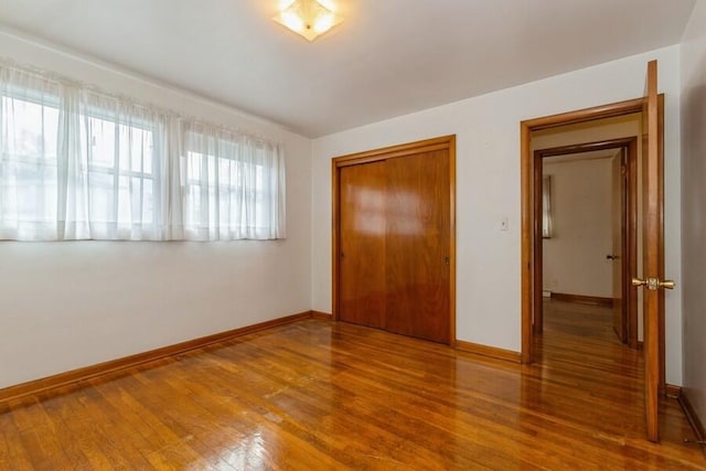 unfurnished bedroom featuring a closet, baseboards, and wood finished floors