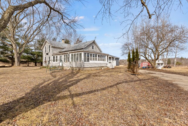 view of front of property featuring a sunroom and a chimney