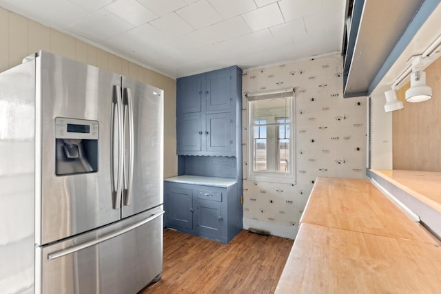 kitchen featuring blue cabinetry, stainless steel refrigerator with ice dispenser, wood finished floors, and wood counters