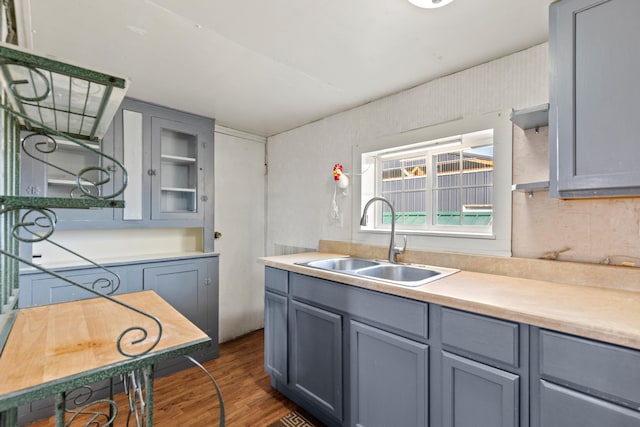 kitchen featuring dark wood-style flooring, gray cabinets, a sink, and light countertops