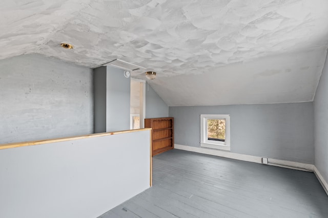 bonus room with baseboards, vaulted ceiling, and wood finished floors