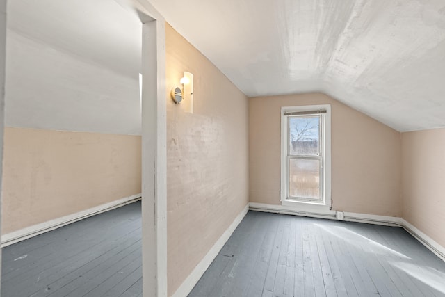 additional living space featuring lofted ceiling, hardwood / wood-style flooring, and baseboards