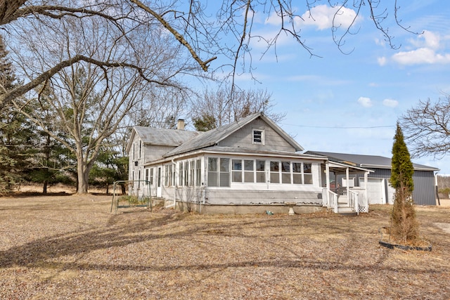 view of front of property with a garage, a chimney, and a sunroom