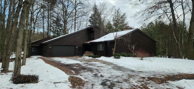 view of snow covered exterior featuring a garage and a chimney