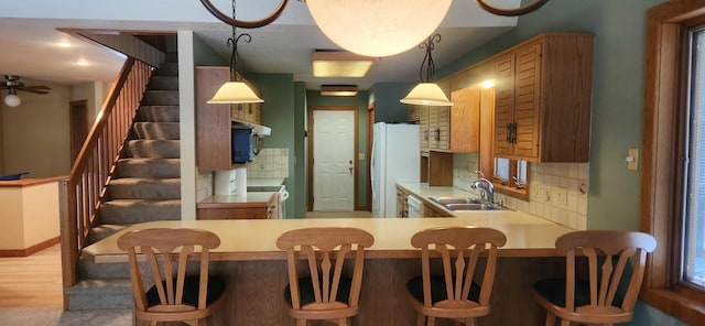 kitchen featuring white appliances, decorative backsplash, light countertops, pendant lighting, and a sink