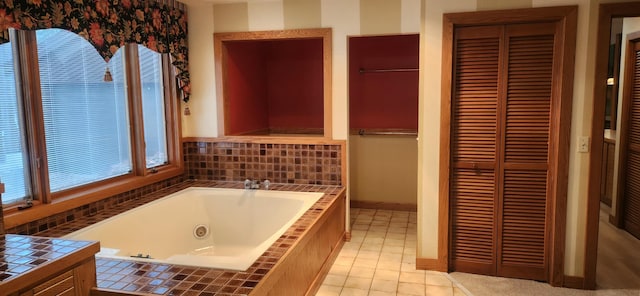 bathroom featuring a jetted tub, tile patterned flooring, baseboards, and a closet