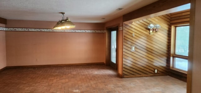 spare room with a healthy amount of sunlight, brick floor, and baseboards