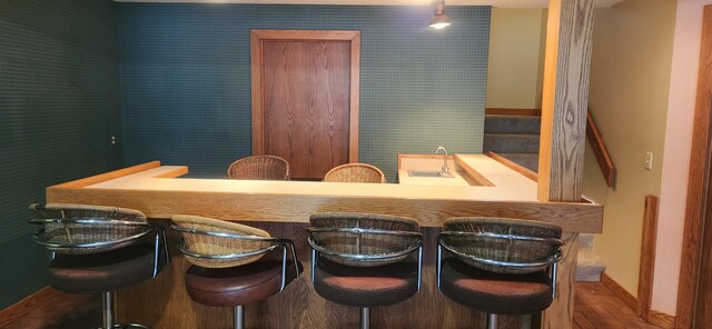 bar with wet bar, a sink, baseboards, and wood finished floors