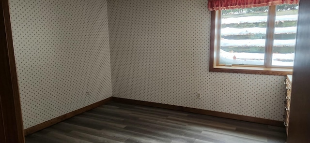 unfurnished room with wallpapered walls, wood finished floors, and baseboards