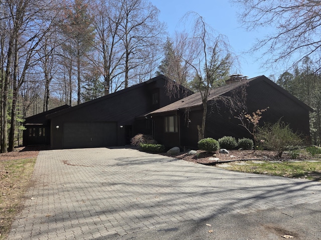 3075 Mineral Springs Trl, Mount Pleasant, MI 48858 - mid-century inspired home with a garage, a chimney, and decorative driveway