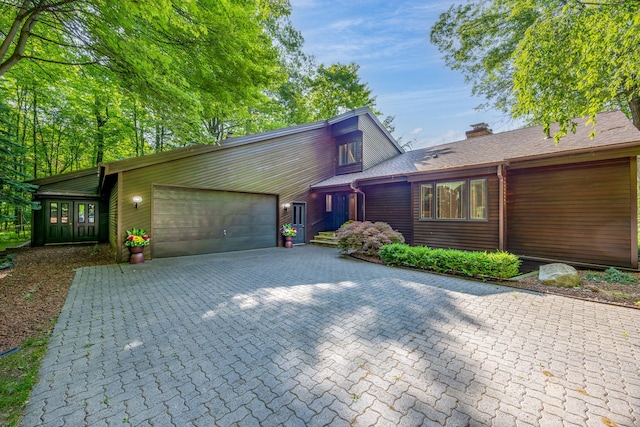 3075 Mineral Springs Trl, Mount Pleasant, MI 48858 - mid-century modern home featuring an attached garage, a chimney, and driveway