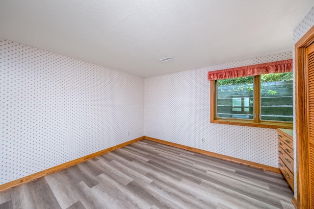 3075 Mineral Springs Trl, Mount Pleasant, MI 48858 - spare room with wallpapered walls and wood finished floors