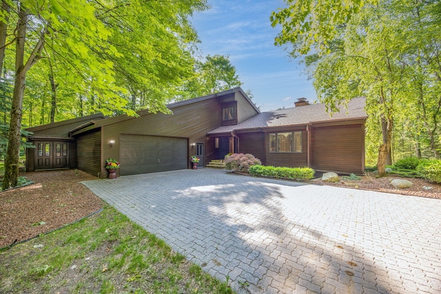 3075 Mineral Springs Trl, Mount Pleasant, MI 48858 - mid-century modern home featuring an attached garage, decorative driveway, and a chimney