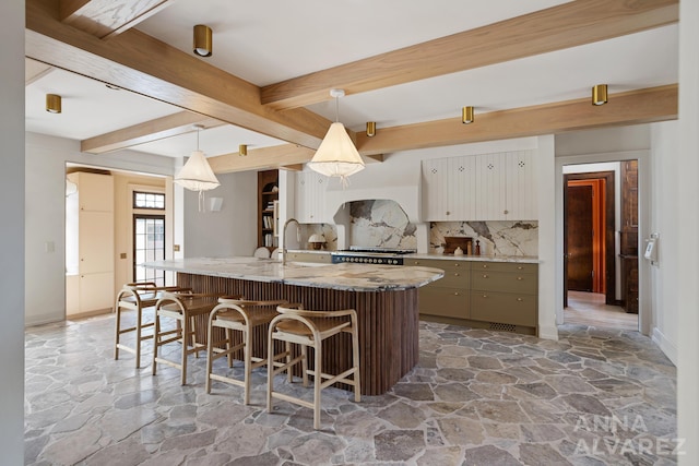 727 Plymouth Rd SE, East Grand Rapids, MI 49506 - kitchen featuring stone flooring, backsplash, a kitchen breakfast bar, a center island with sink, and beam ceiling