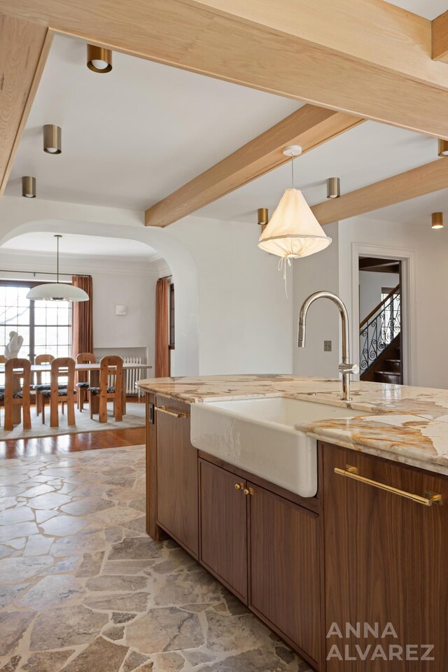 727 Plymouth Rd SE, East Grand Rapids, MI 49506 - kitchen featuring stone floors, arched walkways, beamed ceiling, pendant lighting, and light stone counters