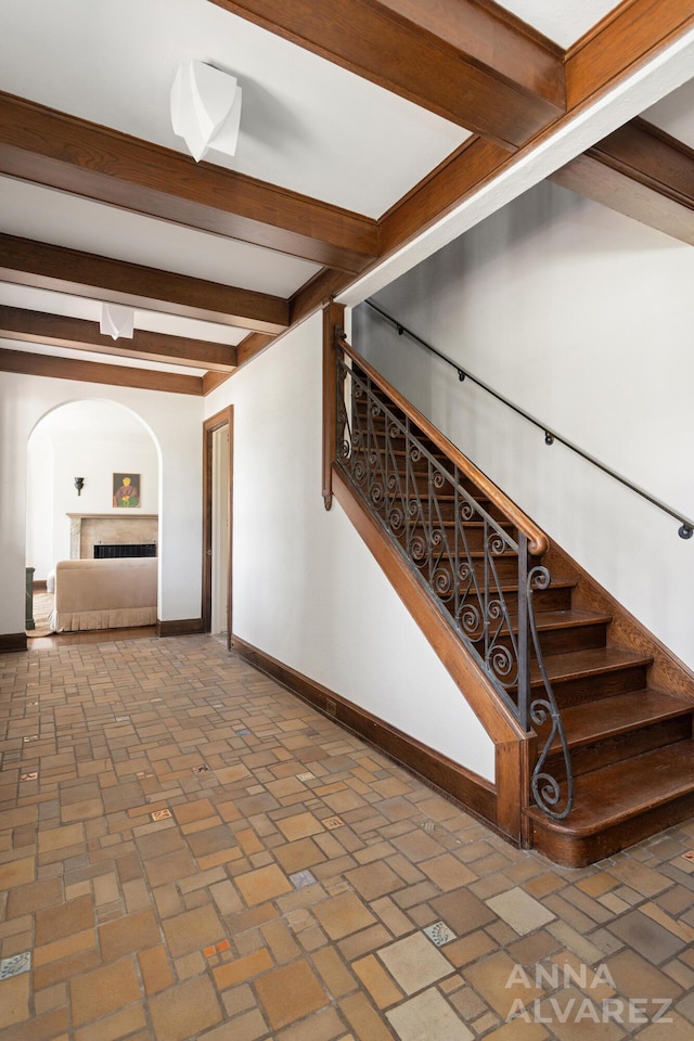727 Plymouth Rd SE, East Grand Rapids, MI 49506 - stairs with brick flooring, beamed ceiling, a fireplace, and arched walkways
