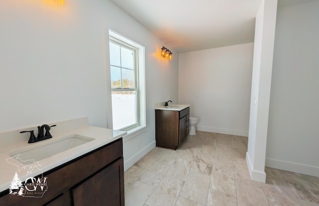 bathroom featuring baseboards, two vanities, a sink, and toilet