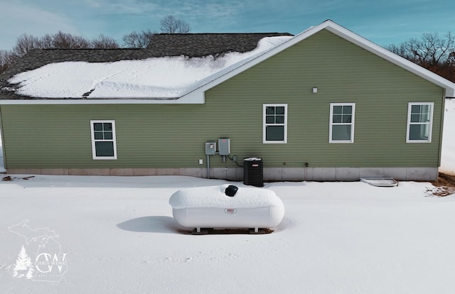 snow covered back of property with central AC