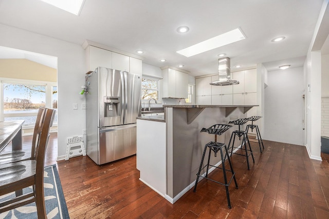 6665 E Lake St, Sand Lake, MI 49343 - kitchen featuring dark wood-style flooring, stainless steel fridge with ice dispenser, a kitchen breakfast bar, island range hood, and a skylight