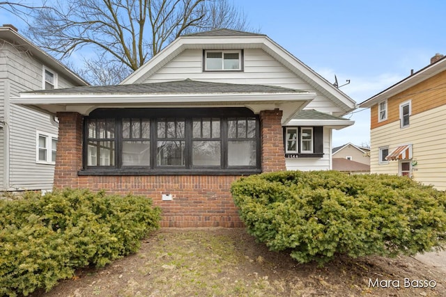 view of front of house featuring brick siding, a gambrel roof, and roof with shingles