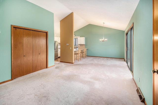 unfurnished bedroom with visible vents, light colored carpet, lofted ceiling, freestanding refrigerator, and an inviting chandelier