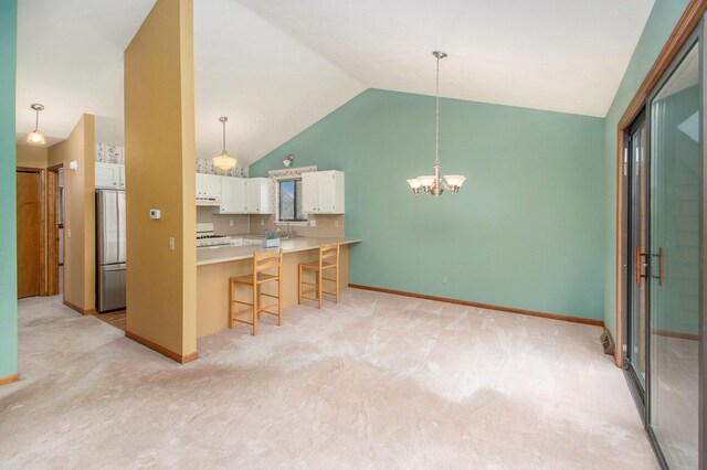 kitchen with a breakfast bar, freestanding refrigerator, light carpet, white cabinets, and under cabinet range hood